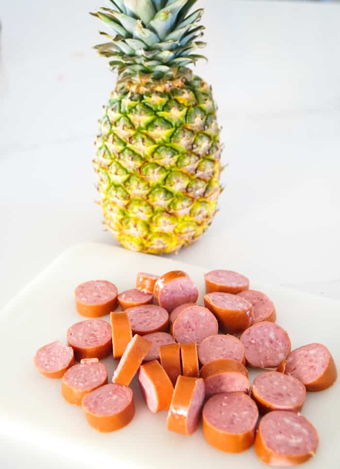 cut up sausage in front of a pineapple